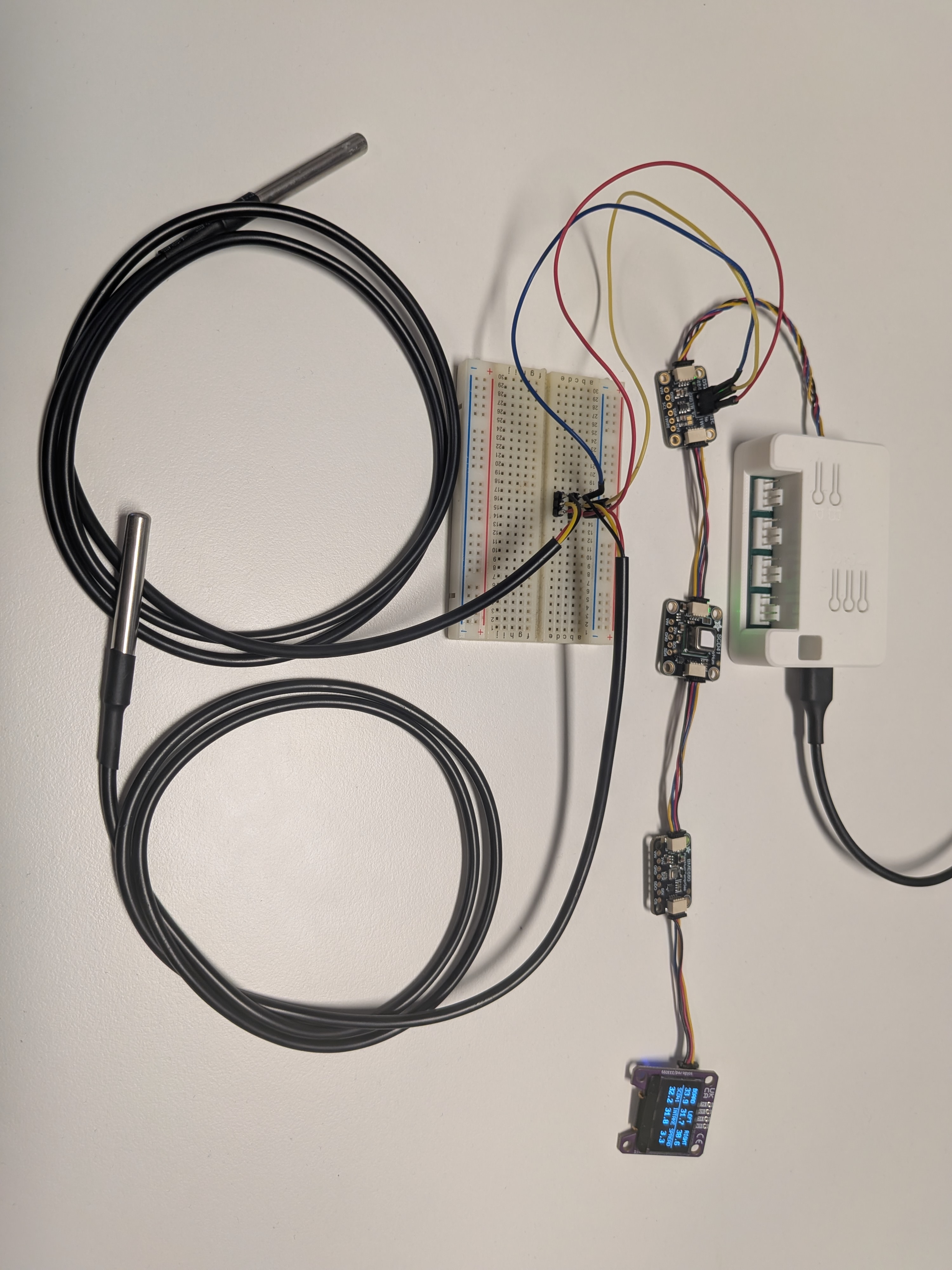 Bench setup with four Qwiic modules chained on one bus: a DS2484 bridge with two DS18B20 probes, an SCD41, a BME680, and an SSD1306 OLED showing the six-cell temperature grid with BOARD at 33.9 and SCD41 at 32.2 degrees Celsius